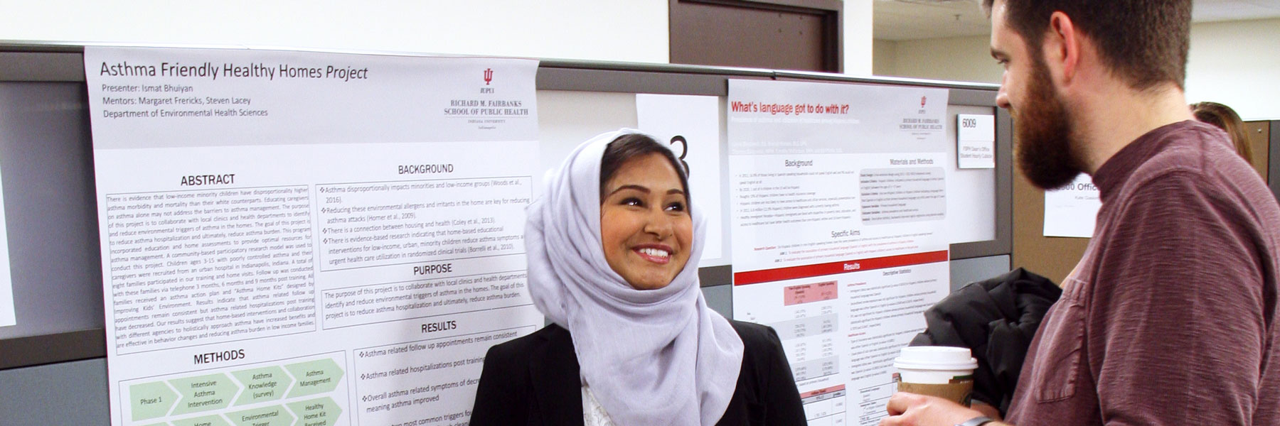 student presenting at poster session speaking to another individual